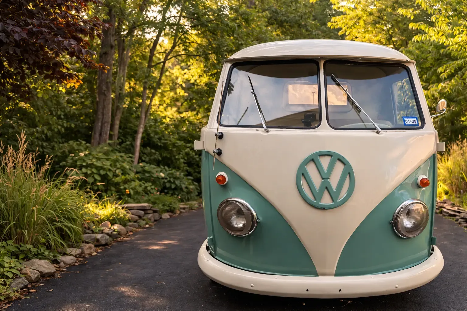 Front view of Rosi, a teal and cream vintage Volkswagen truck, on a driveway lined with trees and ornamental grasses.